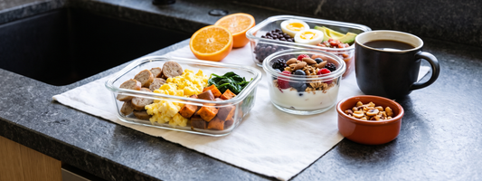 High protein breakfast meal prep containers with eggs, Greek yogurt bowls and roasted sweet potato on a dark countertop